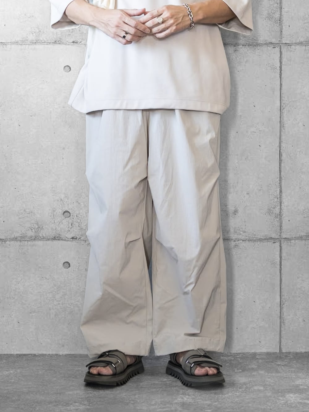 グレー系のその他パンツ、グレー系のサンダル、ベージュ系のTシャツ/カットソーを着用したメンズの夏コーディネートの3枚目の写真