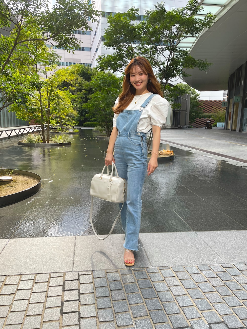ブルー系のサロペット/オーバーオール、ホワイト系のハンドバッグ、ホワイト系のTシャツ/カットソーを着用したレディースの春コーディネートの2枚目の写真