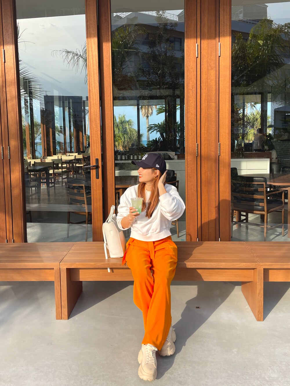 オレンジ系のその他パンツ、ホワイト系のスウェット、ホワイト系のトートバッグを着用したレディースの秋コーディネートの2枚目の写真