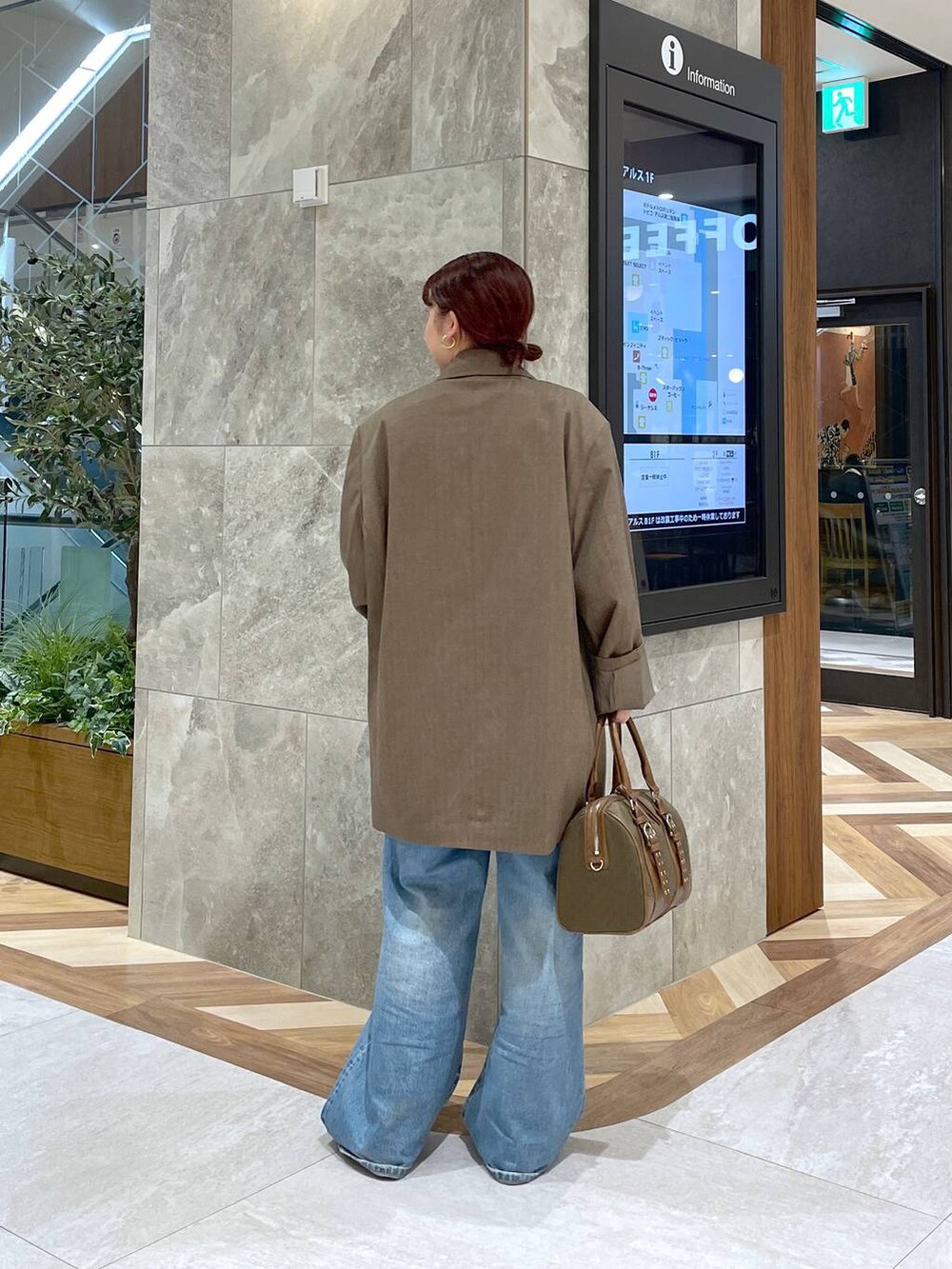 ブルー系のデニムパンツ、グリーン系のボストンバッグ、ブラウン系のテーラードジャケットを着用したレディースの秋コーディネートの2枚目の写真