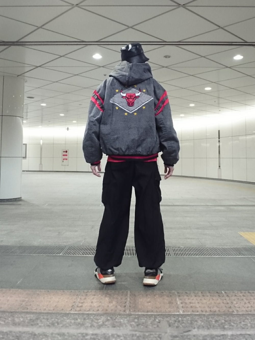グレー系のブルゾン、ブラック系のカーゴパンツ、ブラック系のスニーカーを着用したメンズの冬コーディネートの2枚目の写真