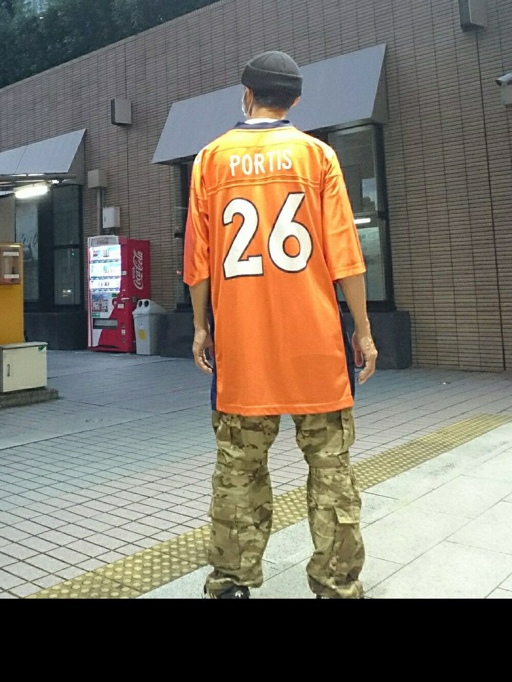 ホワイト系のTシャツ/カットソー、オレンジ系のTシャツ/カットソー、グリーン系のカーゴパンツを着用したメンズの秋コーディネートの2枚目の写真