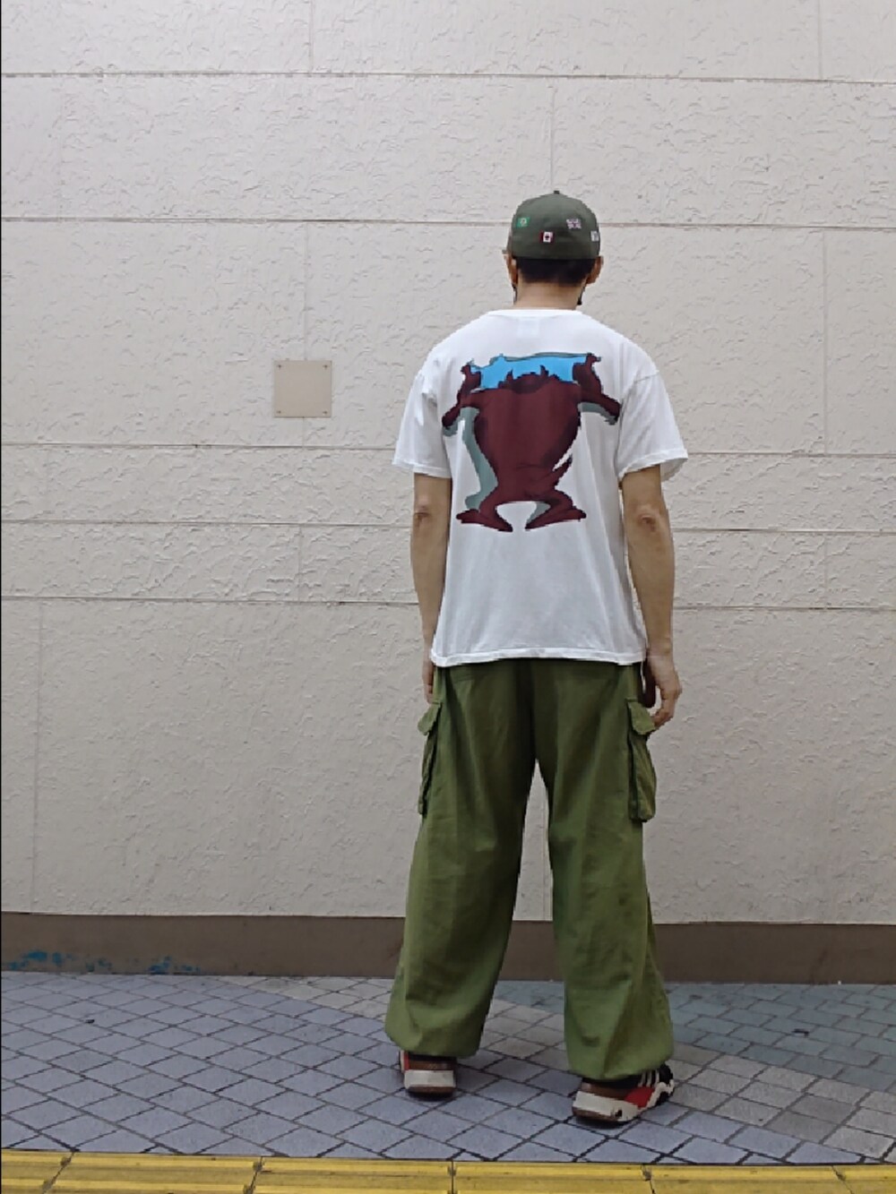 ホワイト系のTシャツ/カットソー、グリーン系のカーゴパンツ、ブラック系のスニーカーを着用したメンズの夏コーディネートの2枚目の写真