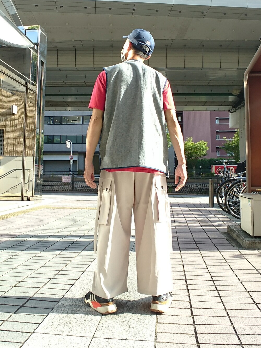 ブルー系のベスト、グレー系のカーゴパンツ、ブラック系のスニーカーを着用したメンズの夏コーディネートの2枚目の写真