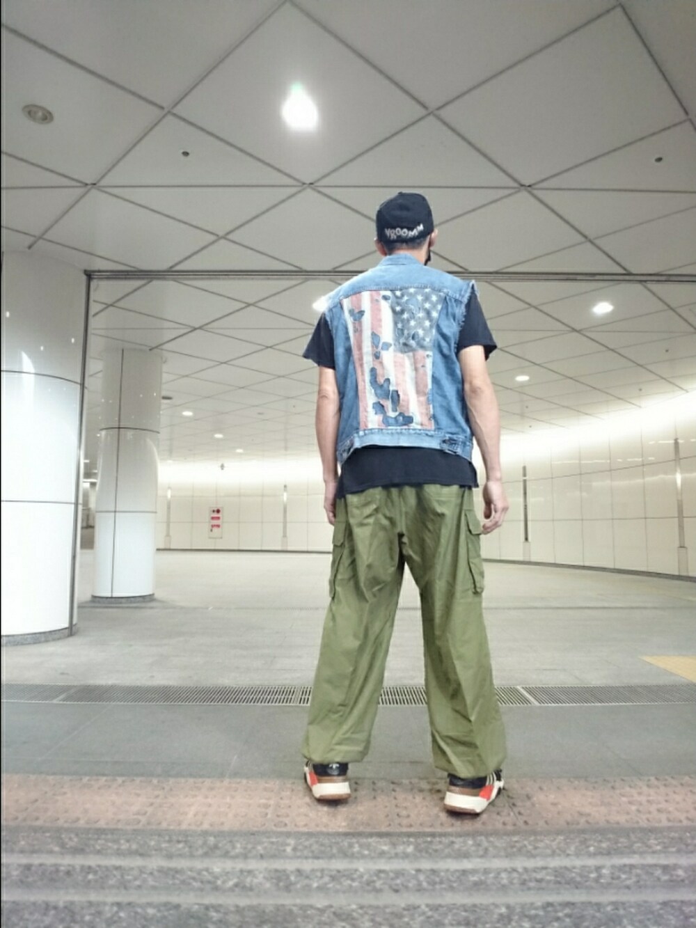 ブルー系のベスト、グリーン系のカーゴパンツ、ブラック系のスニーカーを着用したメンズの夏コーディネートの2枚目の写真