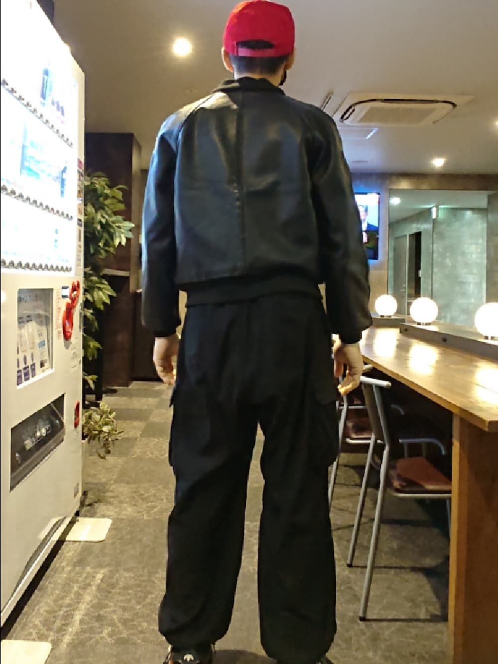 ブラック系のライダースジャケット、ブルー系のTシャツ/カットソー、ブラック系のカーゴパンツを着用したメンズの秋コーディネートの2枚目の写真