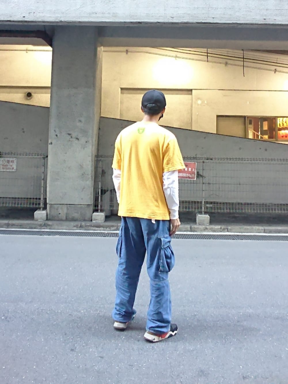 イエロー系のTシャツ/カットソー、ブルー系のカーゴパンツ、ブラック系のスニーカーを着用したメンズの夏コーディネートの2枚目の写真