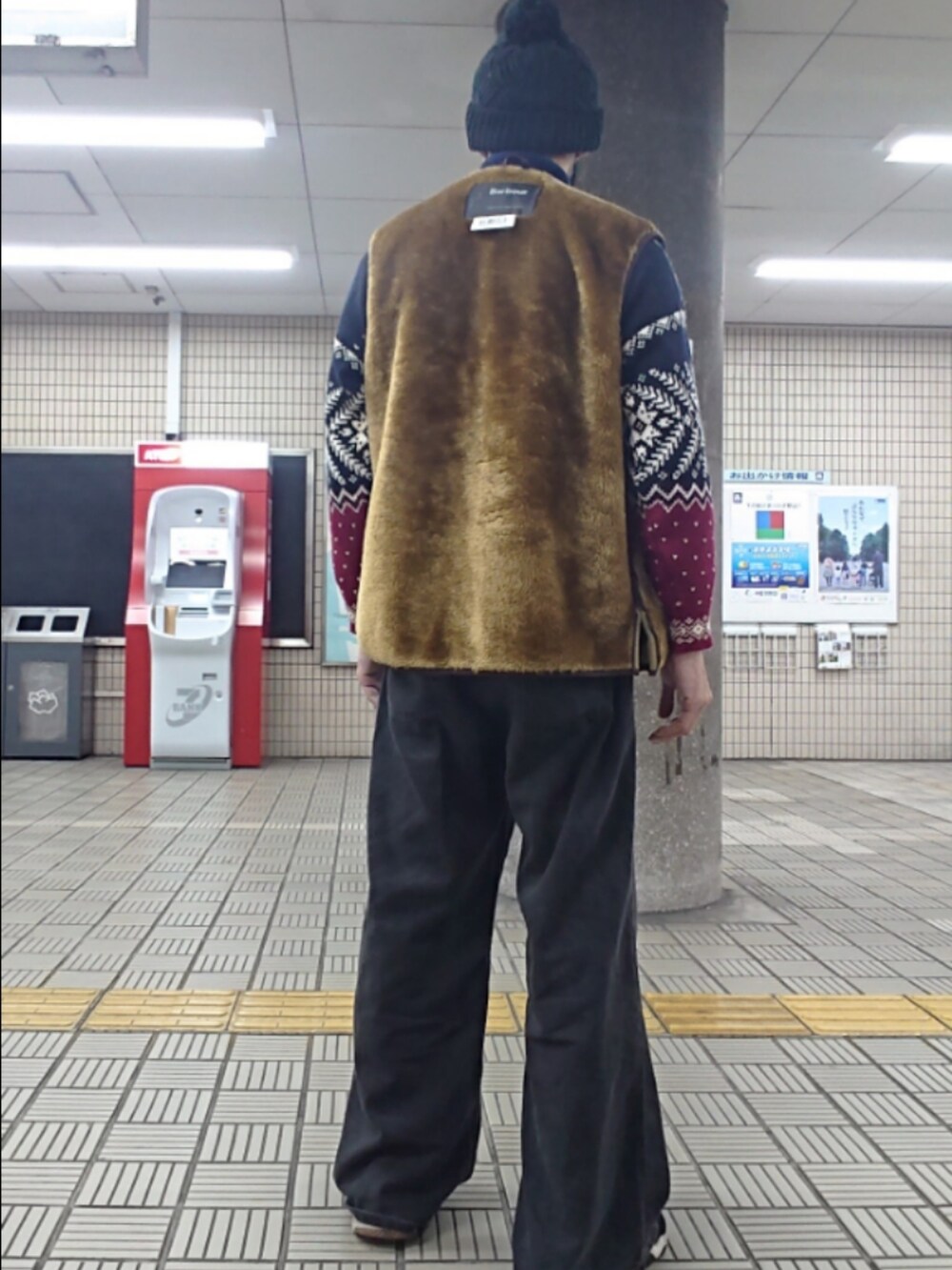 ブラウン系のベスト、ブラック系のデニムパンツ、ブラック系のスニーカーを着用したメンズの春コーディネートの2枚目の写真
