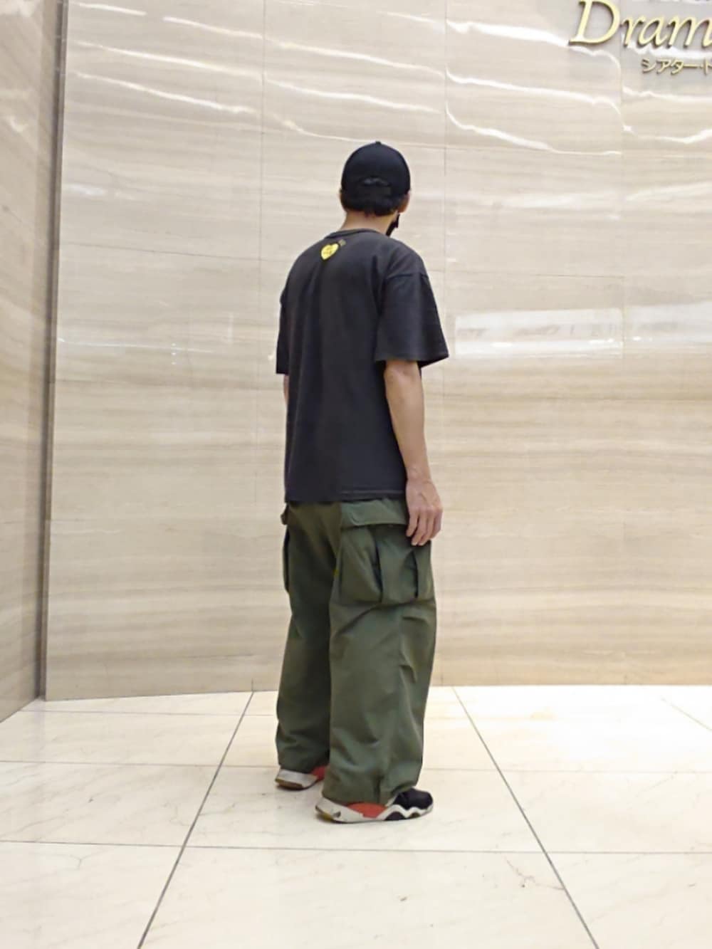 ブラック系のTシャツ/カットソー、グリーン系のカーゴパンツ、ブラック系のスニーカーを着用したメンズの夏コーディネートの2枚目の写真