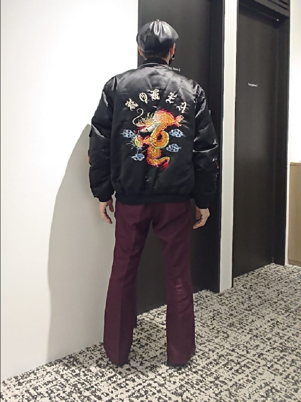 ブラック系のスカジャン、レッド系のスラックス、ブラック系のサンダルを着用したメンズの冬コーディネートの2枚目の写真