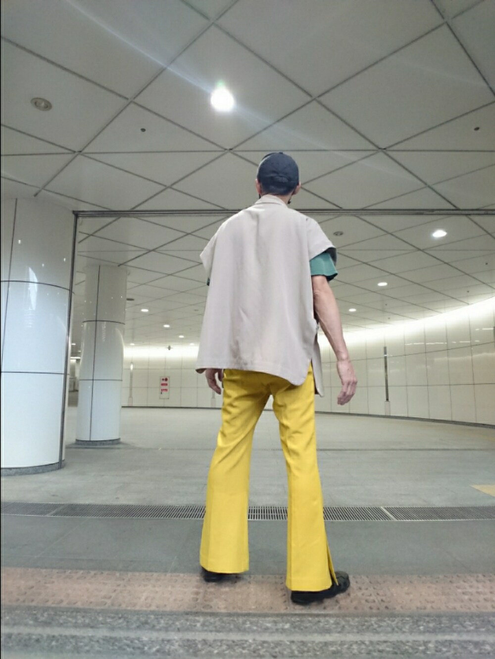 ベージュ系のベスト、イエロー系のその他パンツ、ブラック系のサンダルを着用したメンズの夏コーディネートの2枚目の写真