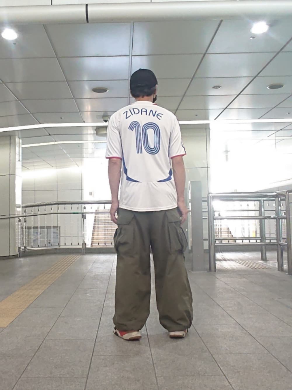 ホワイト系のTシャツ/カットソー、グリーン系のカーゴパンツ、ブラック系のスニーカーを着用したメンズの夏コーディネートの2枚目の写真