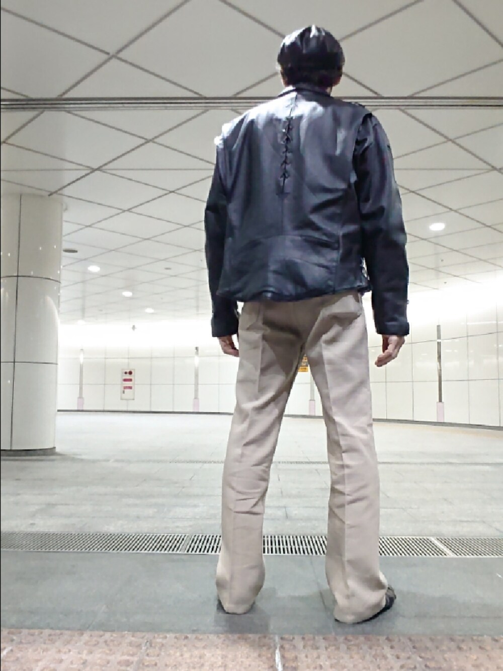 ブラック系のTシャツ/カットソー、ブラック系のライダースジャケット、ベージュ系のスラックスを着用したメンズの秋コーディネートの2枚目の写真