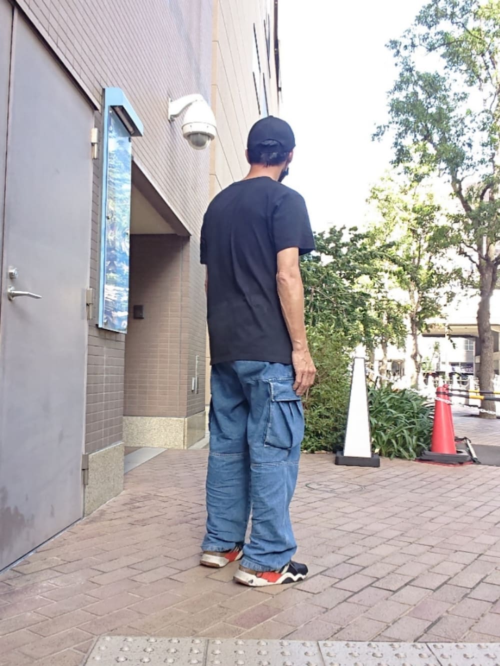 ブラック系のTシャツ/カットソー、ブルー系のカーゴパンツ、ブラック系のスニーカーを着用したメンズの夏コーディネートの2枚目の写真