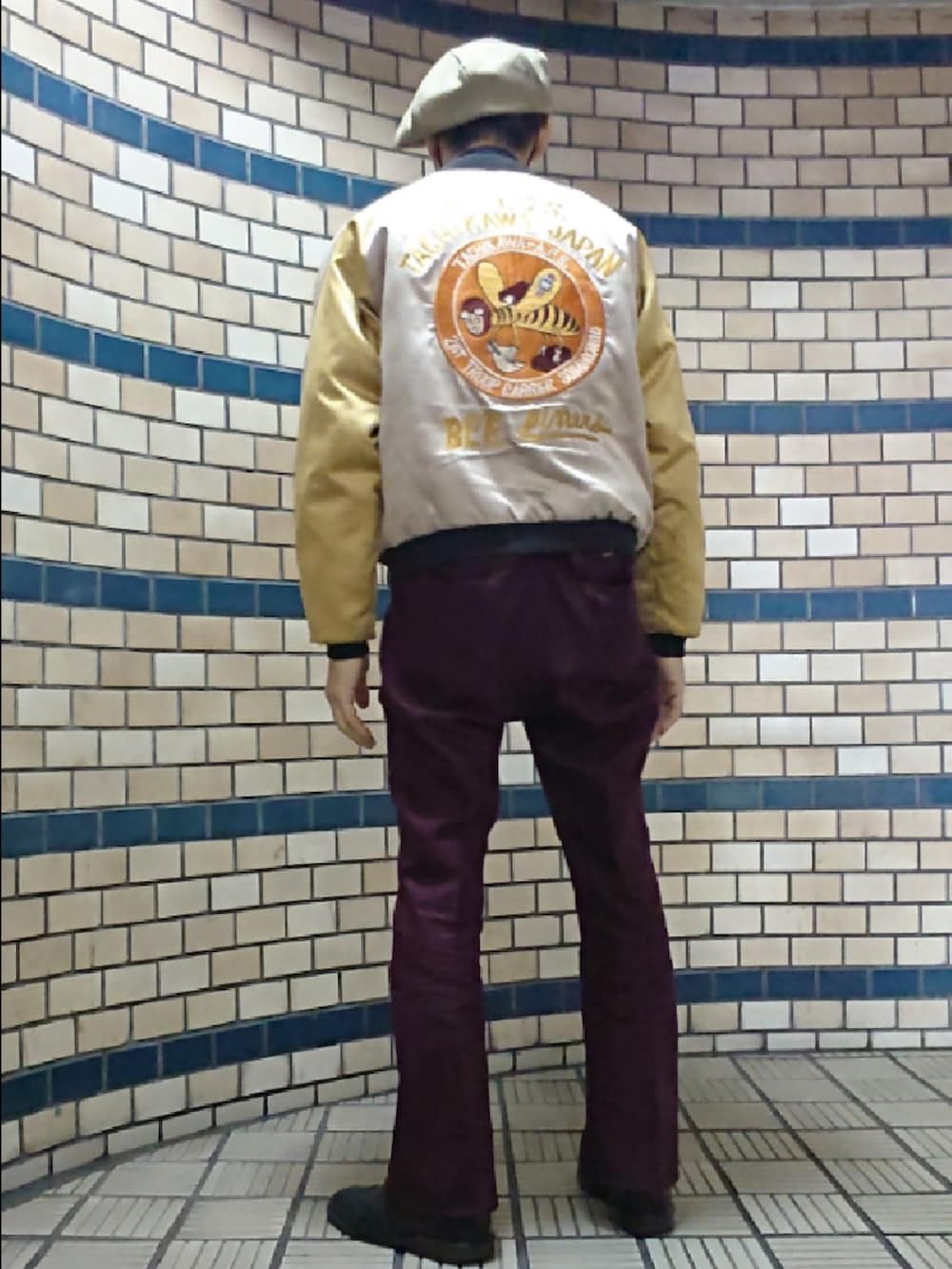 イエロー系のスカジャン、レッド系のスラックス、ブラック系のドレスシューズを着用したメンズの秋コーディネートの2枚目の写真