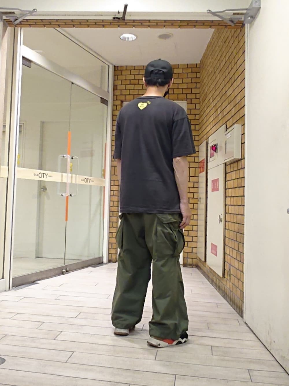 ブラック系のTシャツ/カットソー、グリーン系のカーゴパンツ、ブラック系のスニーカーを着用したメンズの夏コーディネートの2枚目の写真