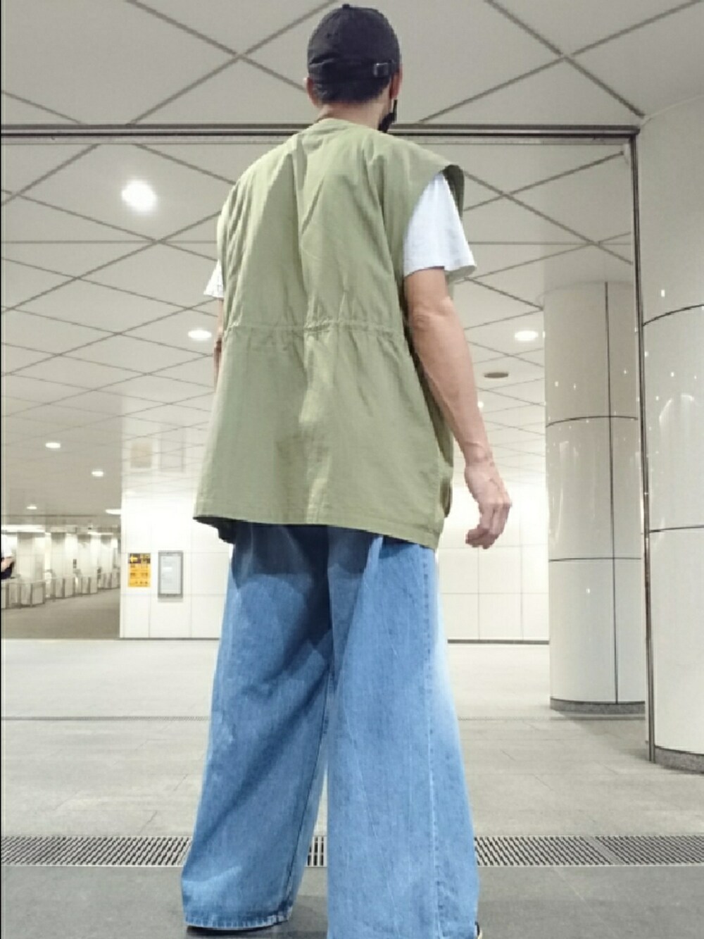 ホワイト系のTシャツ/カットソー、グリーン系のベスト、ブルー系のデニムパンツを着用したメンズの秋コーディネートの2枚目の写真