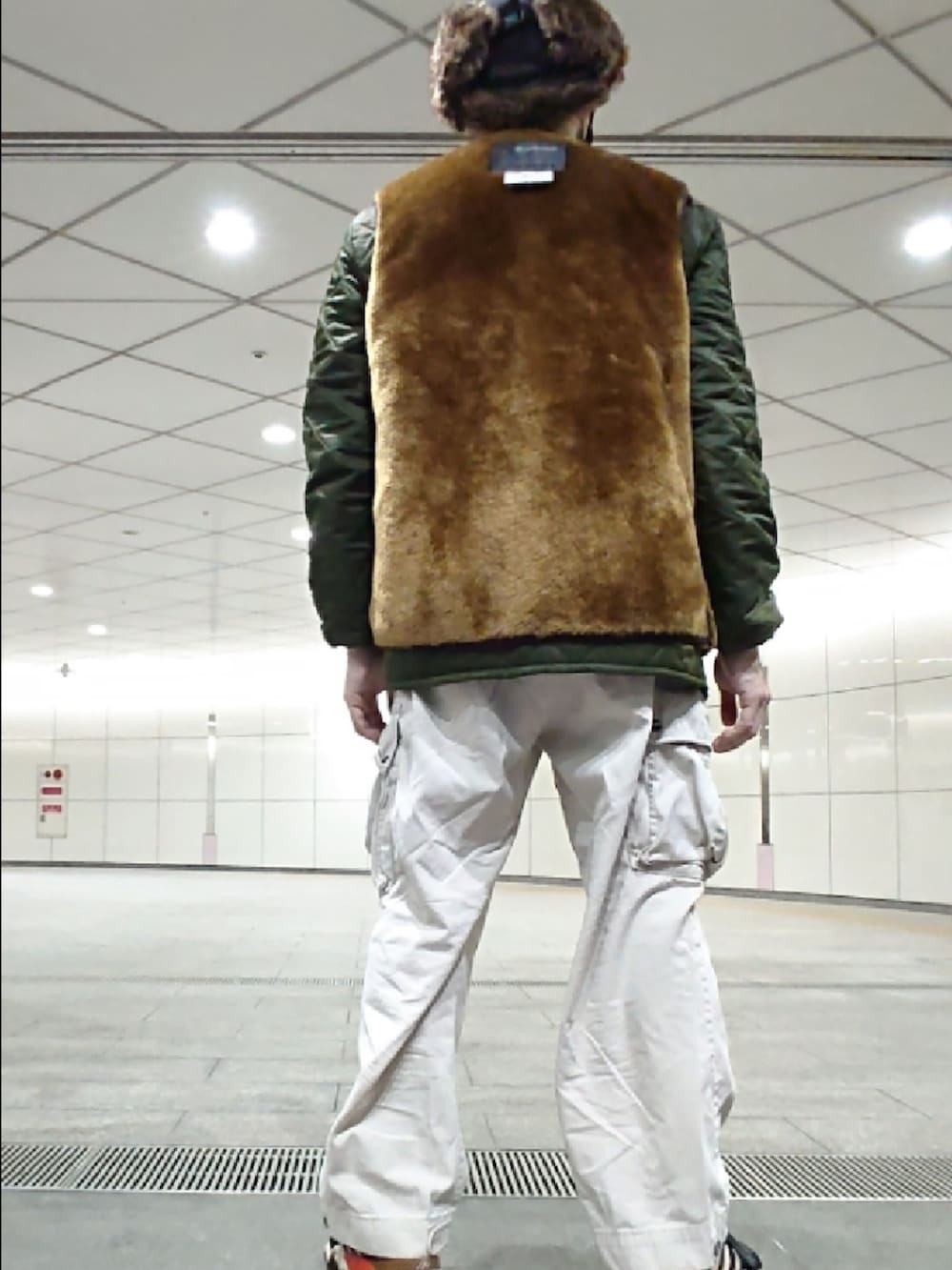 ブラウン系のベスト、グリーン系のジャケット/アウター、ブラック系のスニーカーを着用したメンズの春コーディネートの2枚目の写真