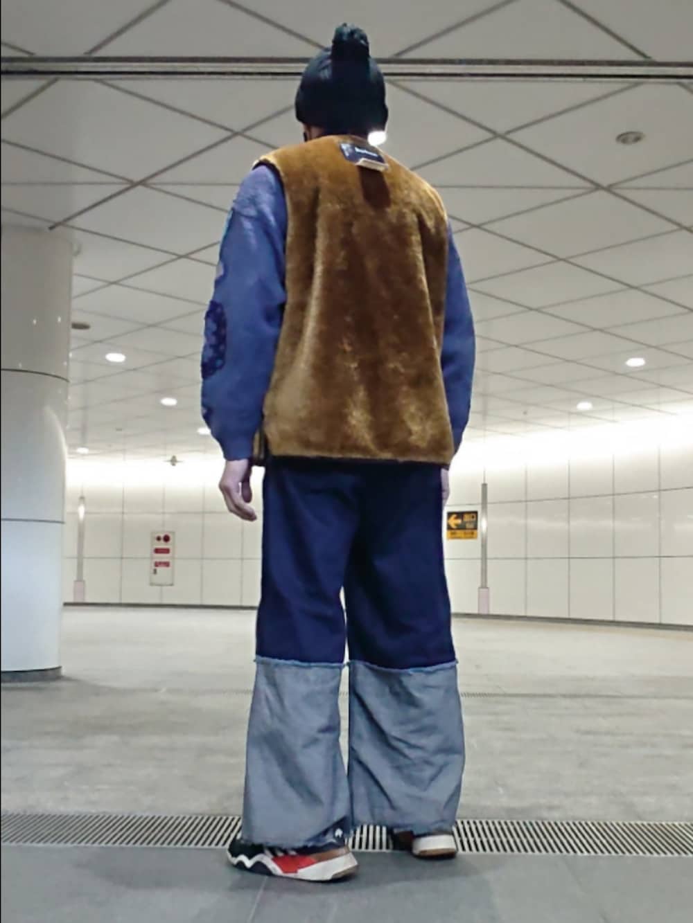 ブルー系のデニムパンツ、ブラウン系のベスト、ブラック系のスニーカーを着用したメンズの冬コーディネートの2枚目の写真