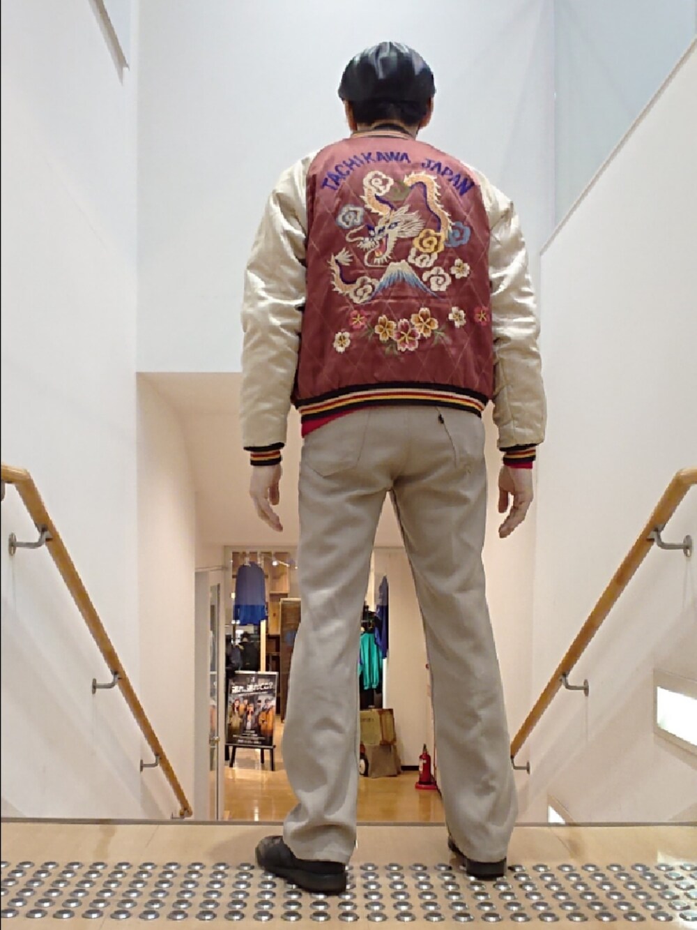 レッド系のスカジャン、ベージュ系のスラックス、ブラック系のドレスシューズを着用したメンズの冬コーディネートの2枚目の写真