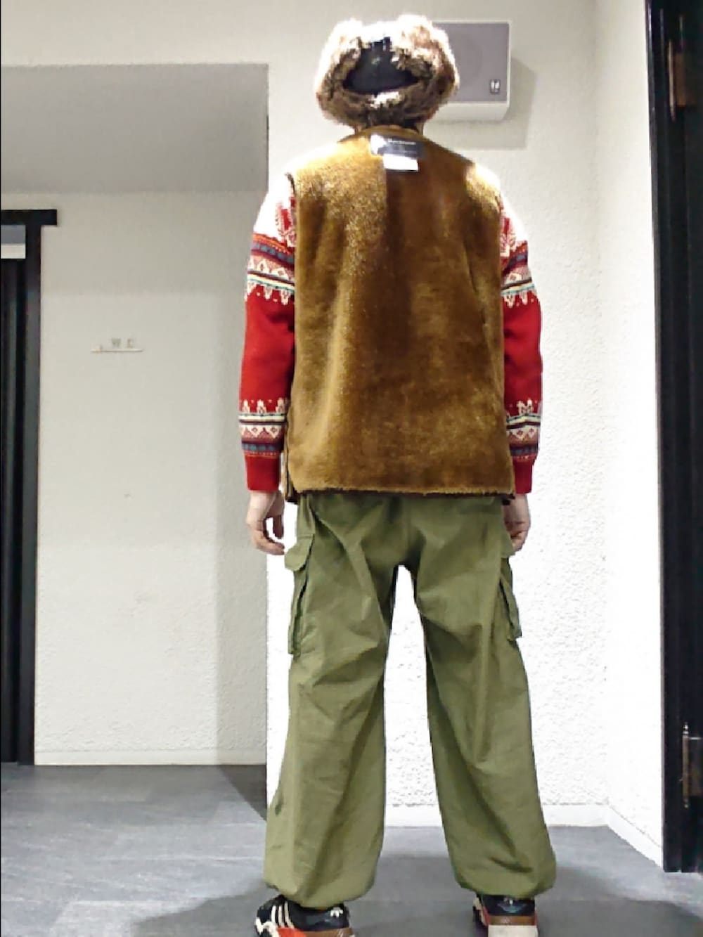 ブラウン系のベスト、グリーン系のカーゴパンツ、ブラック系のスニーカーを着用したメンズの冬コーディネートの2枚目の写真