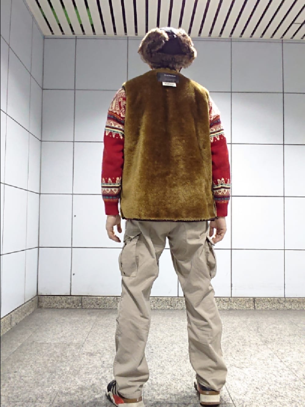 ブラウン系のベスト、グリーン系のカーゴパンツ、ブラック系のスニーカーを着用したメンズの春コーディネートの2枚目の写真