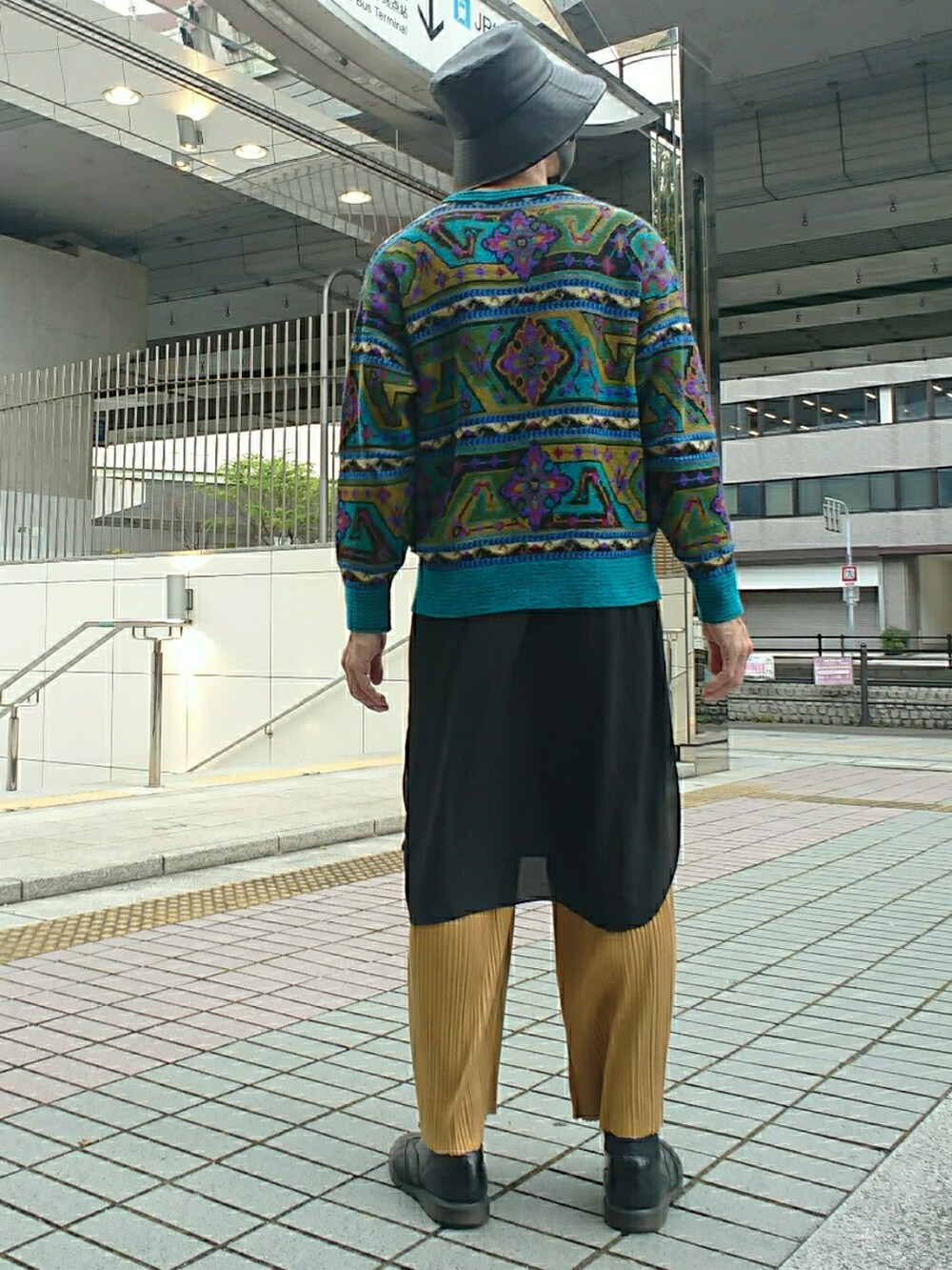 ブルー系のニット/セーター、イエロー系のその他パンツ、ブラック系のドレスシューズを着用したメンズの春コーディネートの2枚目の写真