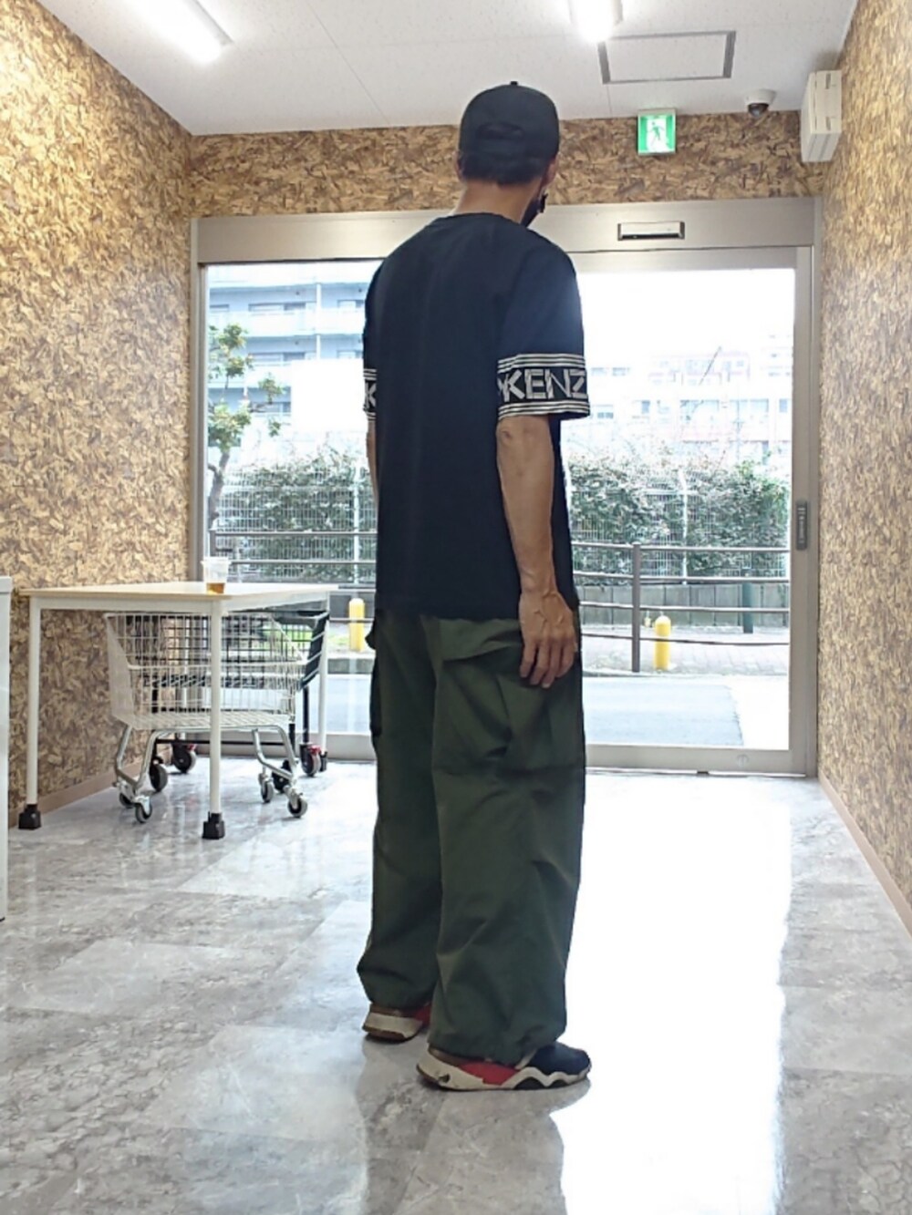 ブラック系のTシャツ/カットソー、グリーン系のカーゴパンツ、ブラック系のスニーカーを着用したメンズの夏コーディネートの2枚目の写真