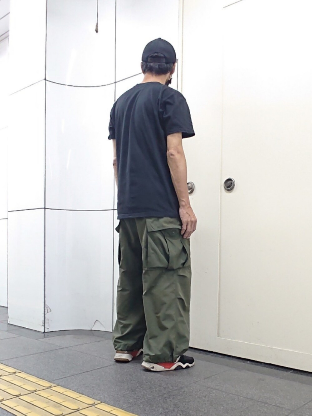 ブラック系のTシャツ/カットソー、グリーン系のカーゴパンツ、ブラック系のスニーカーを着用したメンズの夏コーディネートの2枚目の写真