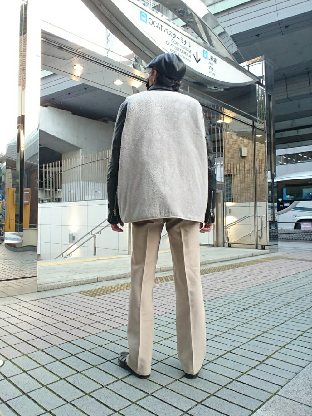 グレー系のベスト、ブラック系のライダースジャケット、ベージュ系のスラックスを着用したメンズの冬コーディネートの2枚目の写真