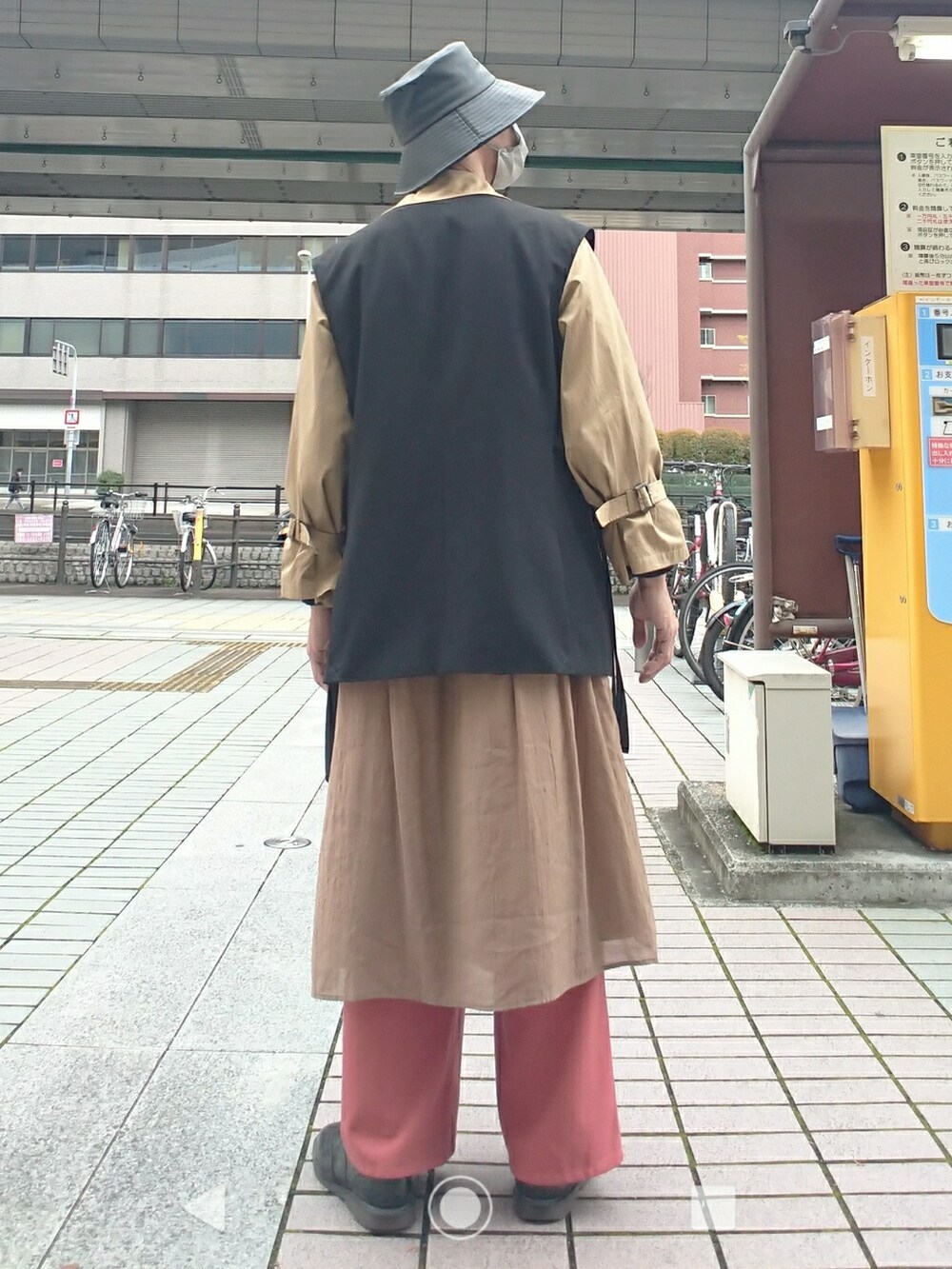 ブラック系のベスト、ブラック系のニット/セーター、ブラウン系のトレンチコートを着用したメンズの春コーディネートの3枚目の写真