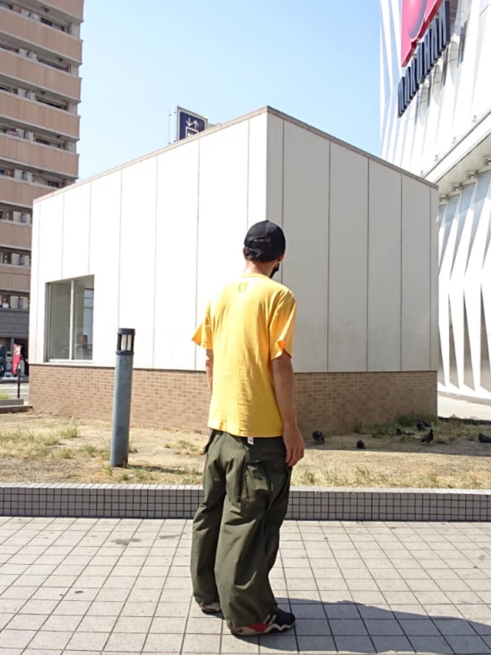 イエロー系のTシャツ/カットソー、グリーン系のカーゴパンツ、ブラック系のスニーカーを着用したメンズの夏コーディネートの2枚目の写真