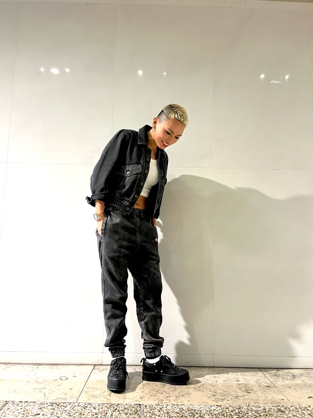 ブラック系のスニーカー、ブラック系のデニムジャケット、ブラック系のデニムパンツを着用したレディースの冬コーディネートの2枚目の写真