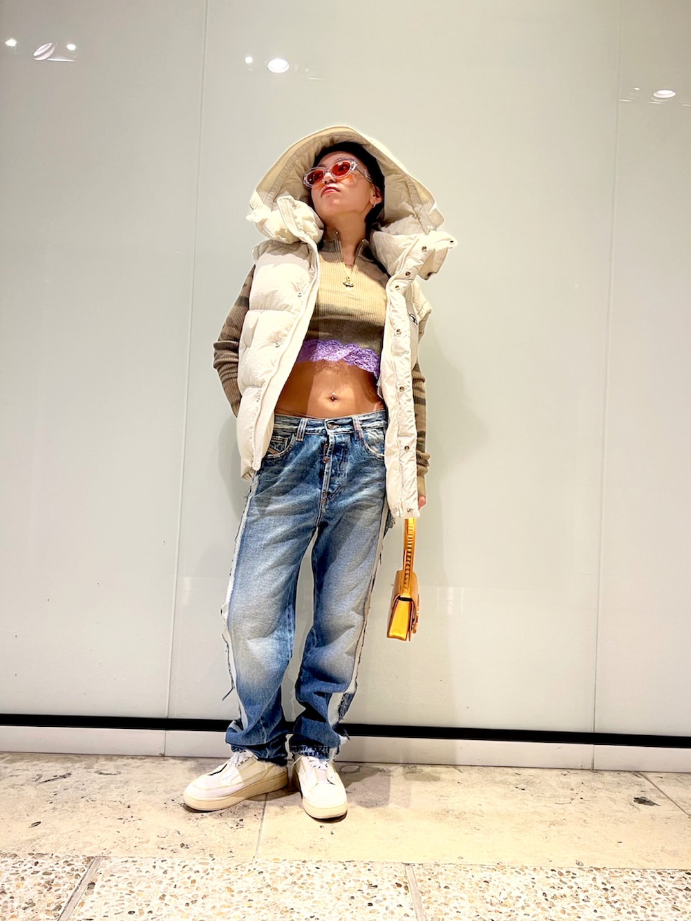 グリーン系のニット/セーター、ブルー系のデニムパンツ、ホワイト系のスニーカーを着用したレディースの秋コーディネートの2枚目の写真