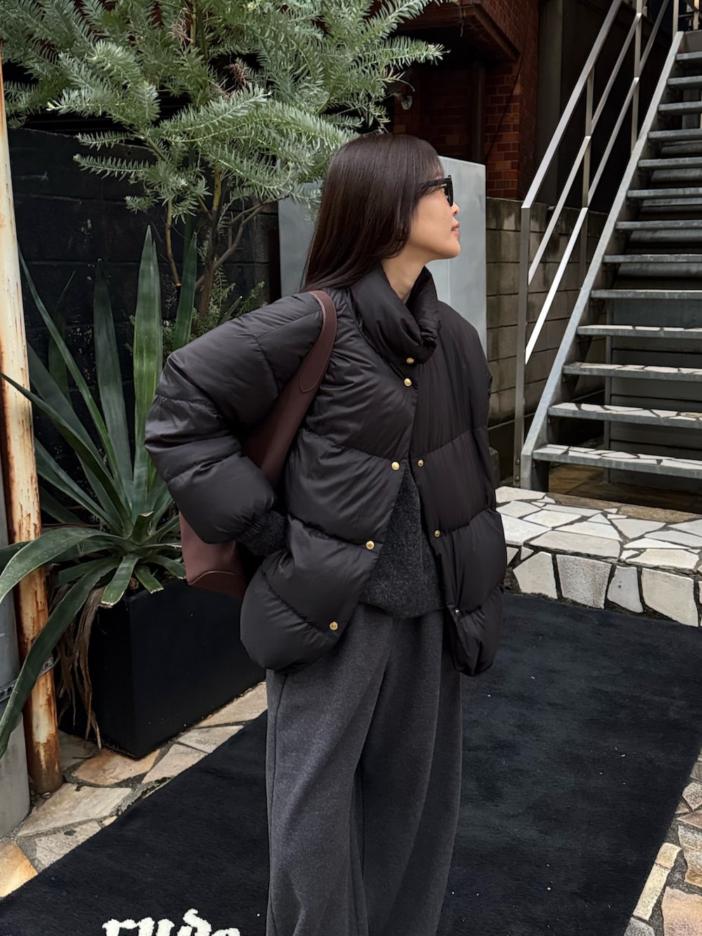 ブラック系のダウンジャケット/コート、ブラック系のその他パンツ、グレー系のニット/セーターを着用したレディースの冬コーディネートの3枚目の写真