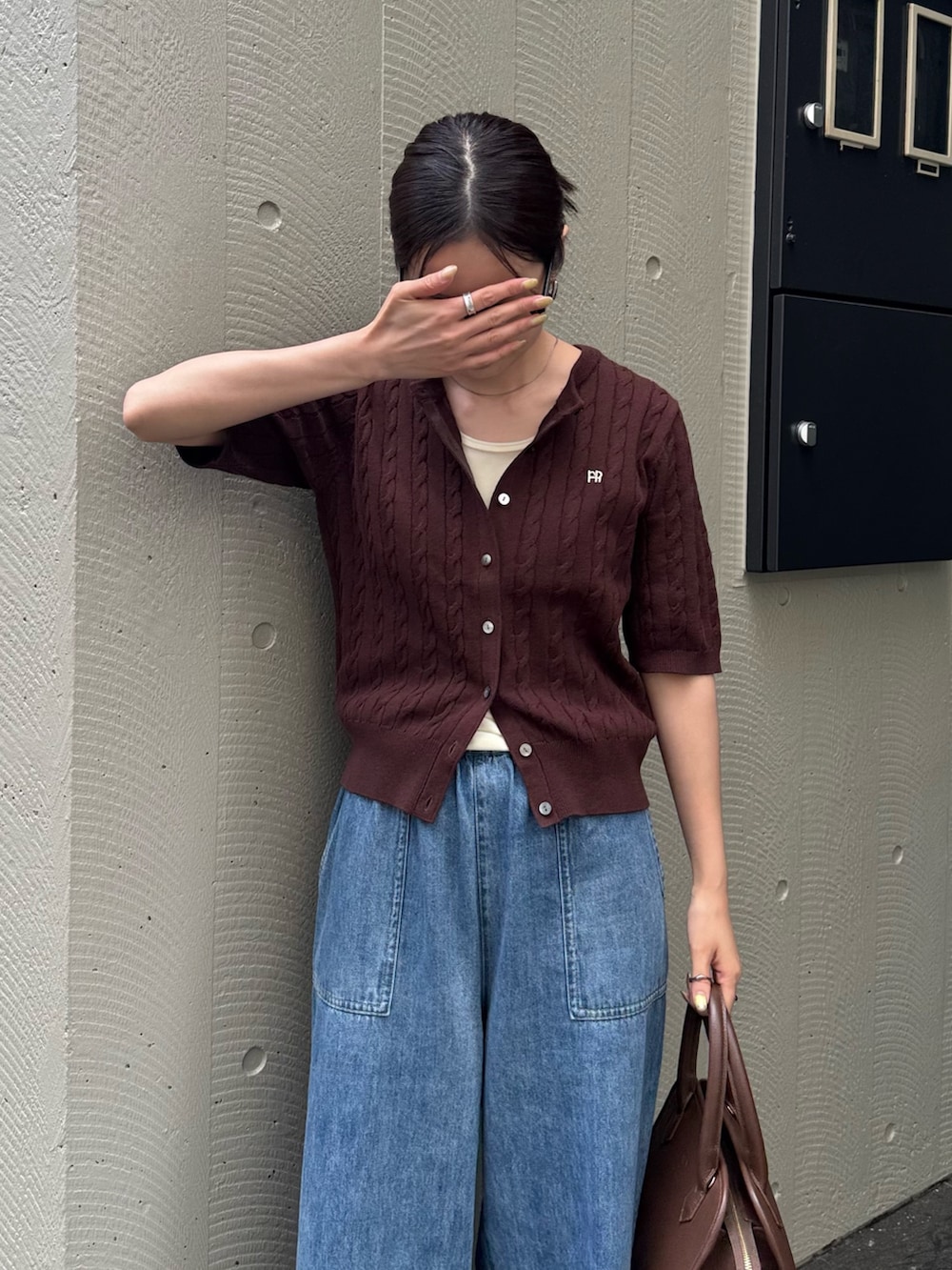ブルー系のデニムパンツ、ブラウン系のショルダーバッグ、ブラウン系のカーディガン/ボレロを着用したレディースの夏コーディネートの3枚目の写真