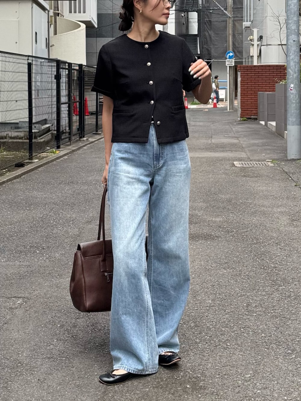 ブラック系のノーカラージャケット、ブルー系のデニムパンツ、ブラウン系のショルダーバッグを着用したレディースの春コーディネートの2枚目の写真