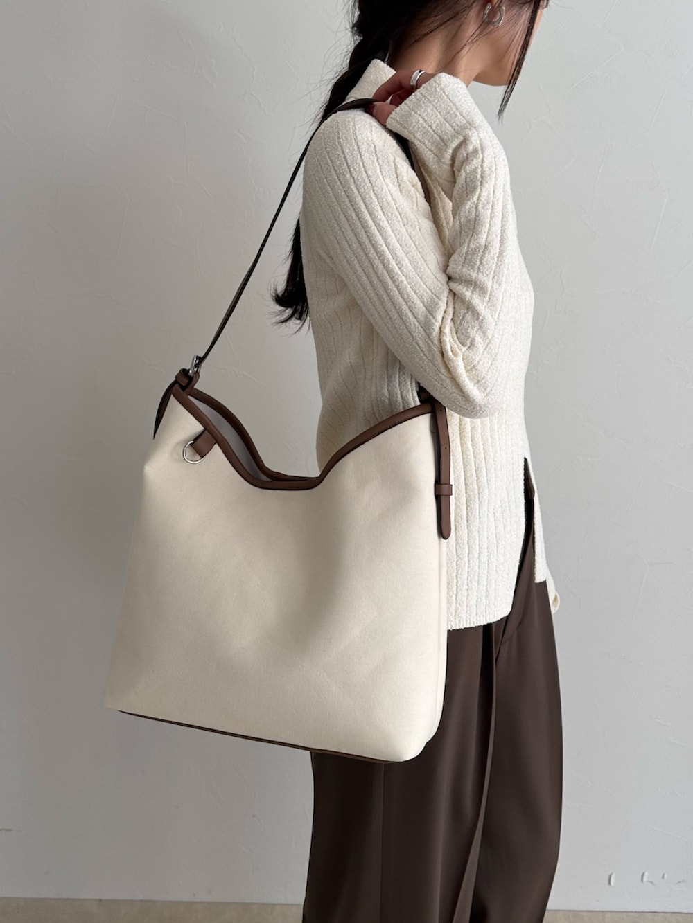 ホワイト系のニット/セーター、ブラウン系のスラックス、ホワイト系のショルダーバッグを着用したレディースの冬コーディネートの6枚目の写真