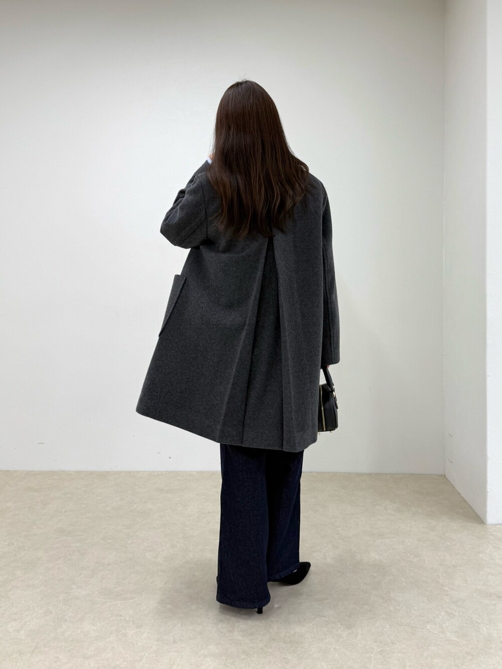 グレー系のダッフルコート、ブルー系のデニムパンツ、グレー系のニット/セーターを着用したレディースの秋コーディネートの3枚目の写真