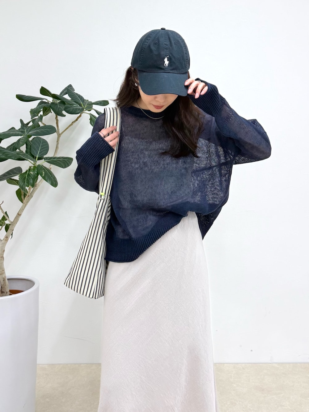 ブルー系のニット/セーター、ブラック系のショルダーバッグ、ベージュ系のスカートを着用したレディースの春コーディネートの4枚目の写真