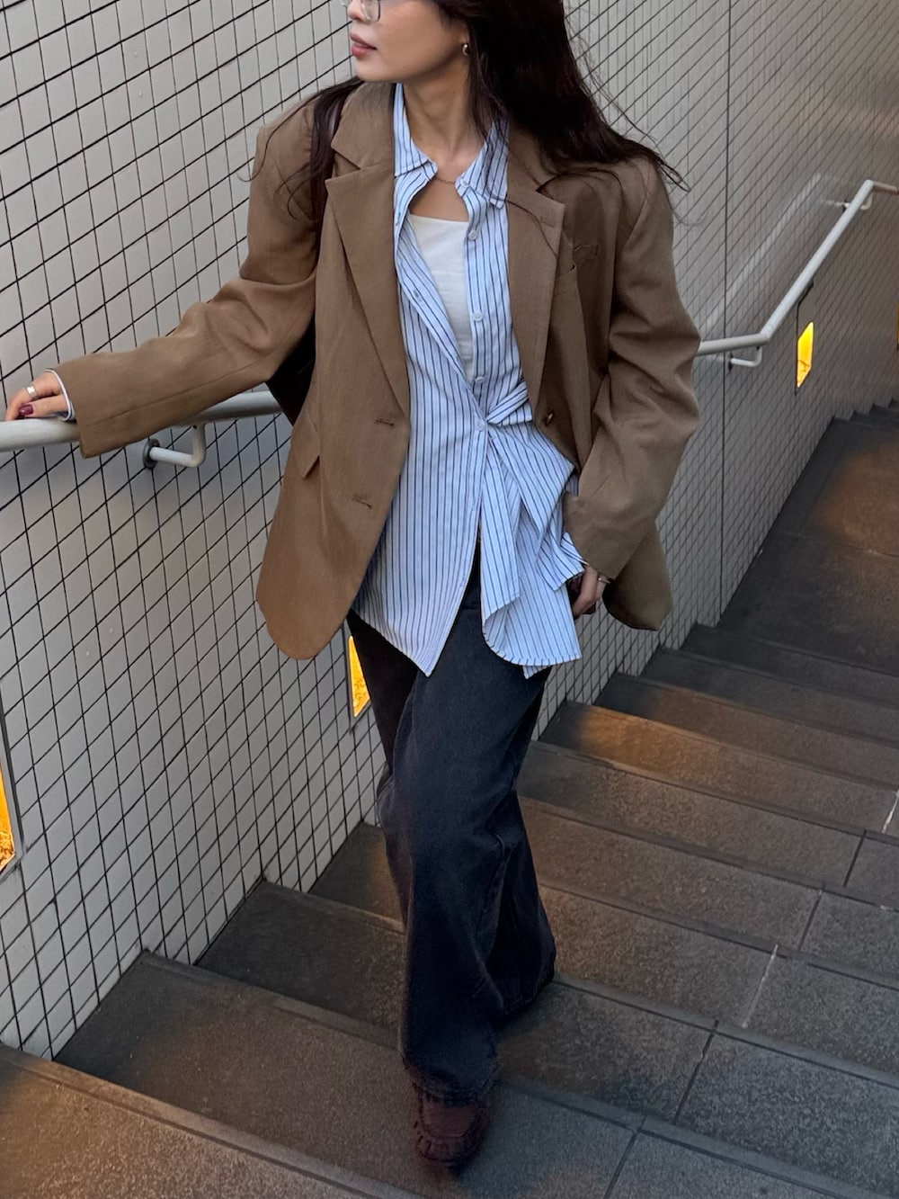 ブラウン系のテーラードジャケット、ブルー系のシャツ/ブラウス、ブラック系のデニムパンツを着用したレディースの冬コーディネートの4枚目の写真