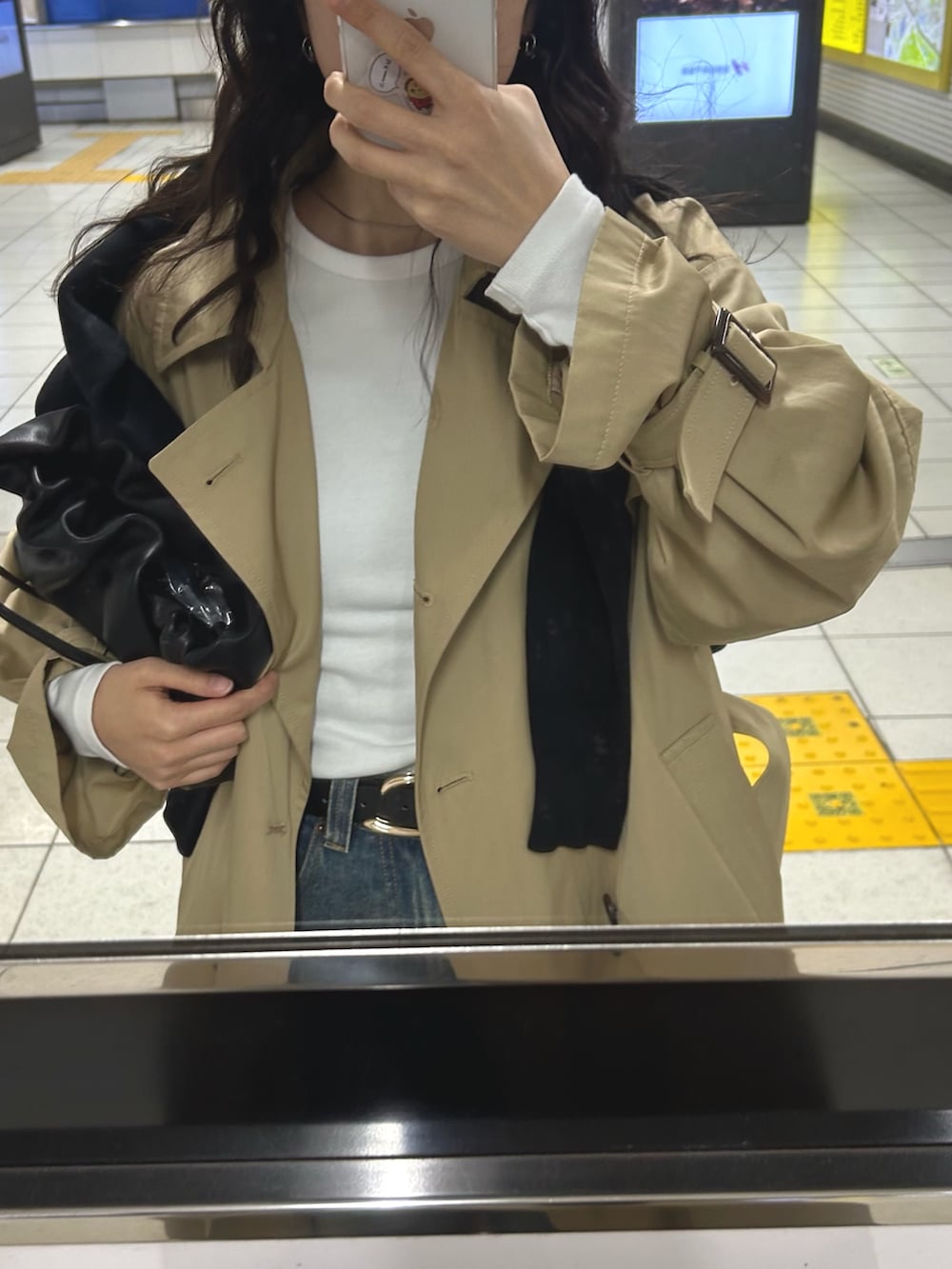 ベージュ系のトレンチコート、ブルー系のデニムパンツ、ブラック系のショルダーバッグを着用したレディースの冬コーディネートの5枚目の写真