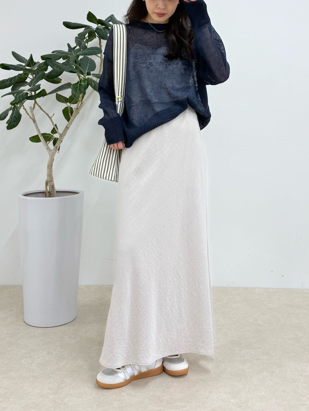 ブルー系のニット/セーター、ブラック系のショルダーバッグ、ベージュ系のスカートを着用したレディースの春コーディネートの3枚目の写真