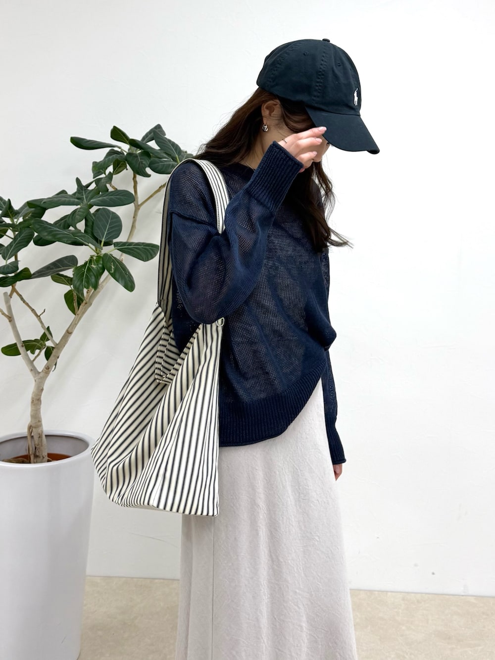 ブルー系のニット/セーター、ブラック系のショルダーバッグ、ベージュ系のスカートを着用したレディースの春コーディネートの5枚目の写真