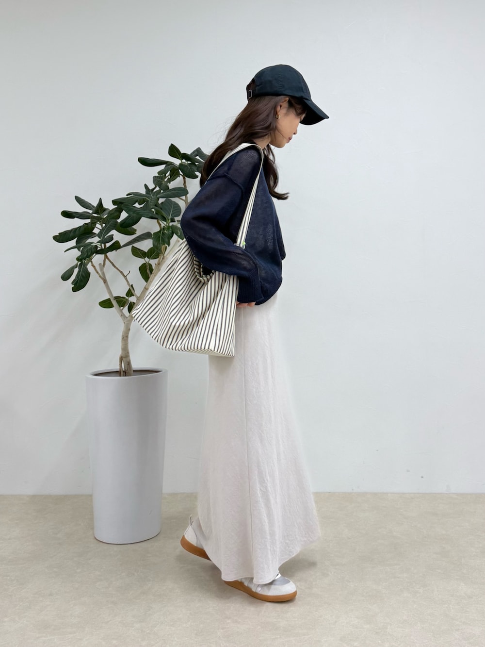 ブルー系のニット/セーター、ブラック系のショルダーバッグ、ベージュ系のスカートを着用したレディースの春コーディネートの2枚目の写真