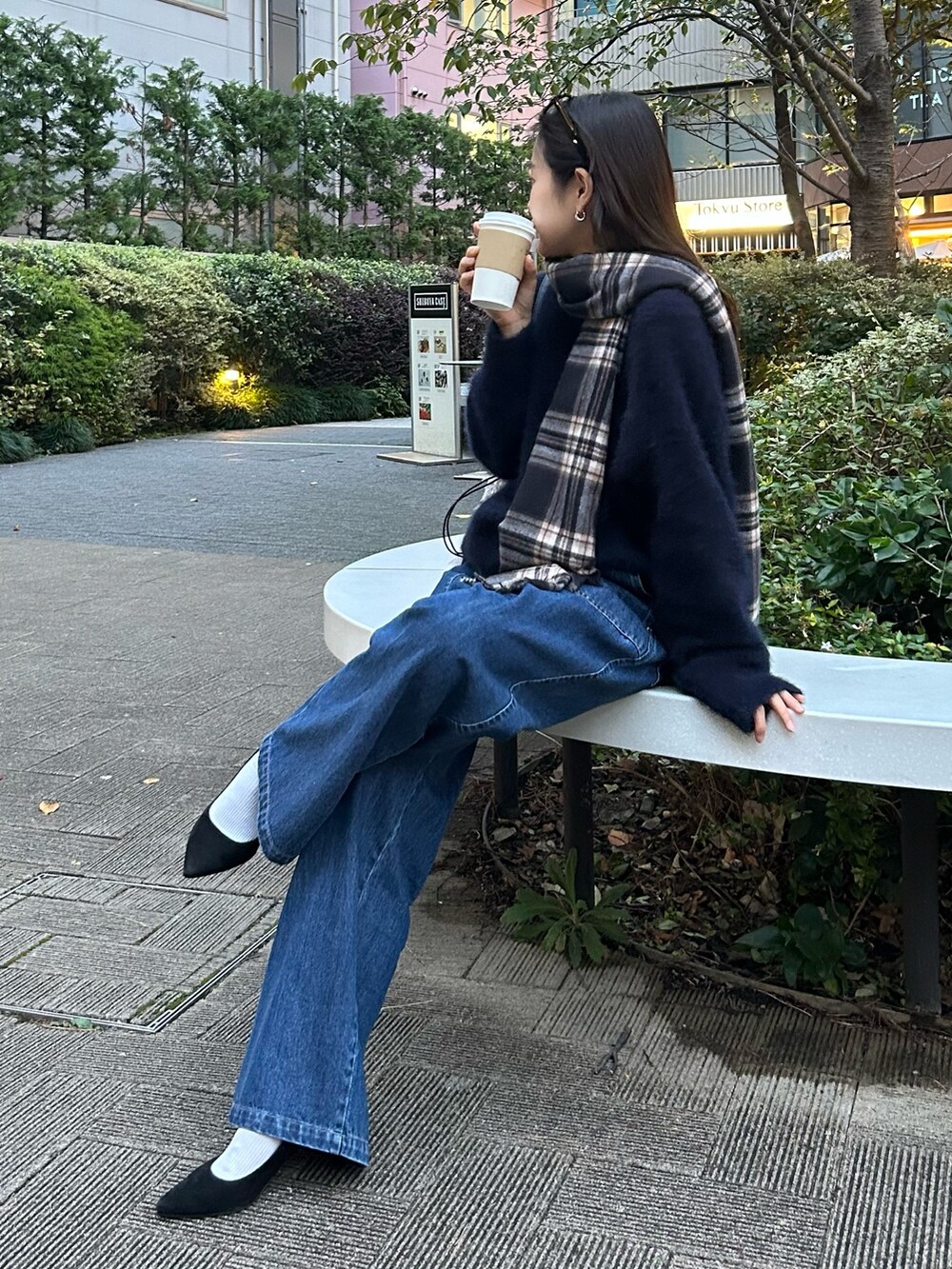 ブルー系のニット/セーター、ブルー系のデニムパンツ、グレー系のハンドバッグを着用したレディースの秋コーディネートの2枚目の写真