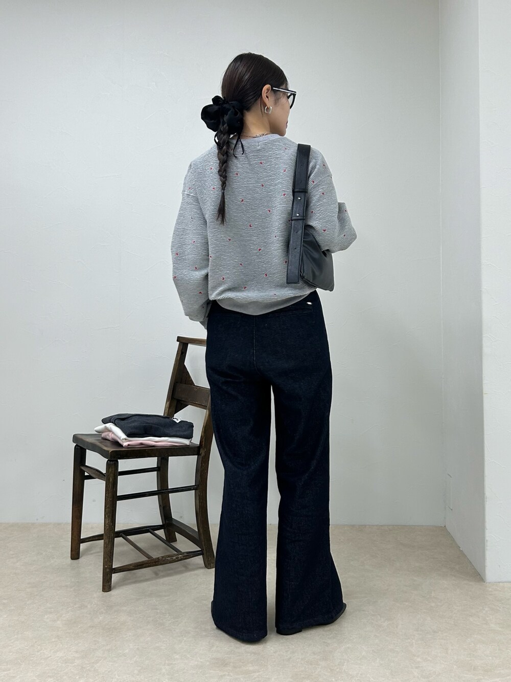 グレー系のスウェット、ブルー系のデニムパンツ、ブラック系のショルダーバッグを着用したレディースの秋コーディネートの3枚目の写真
