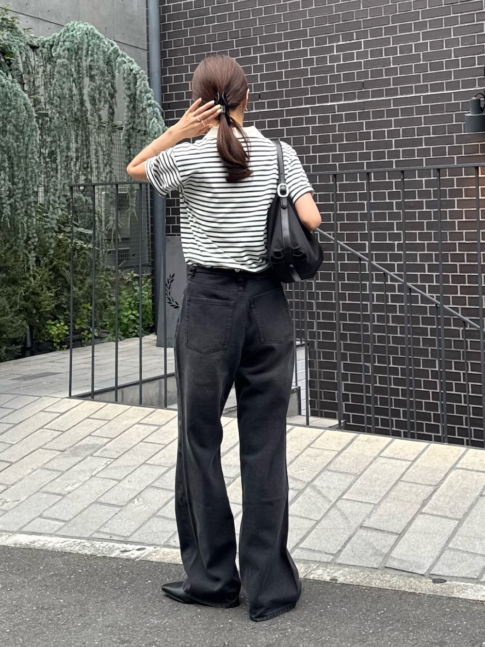 グリーン系のポロシャツ、ブラック系のデニムパンツ、ブラック系のパンプスを着用したレディースの夏コーディネートの2枚目の写真