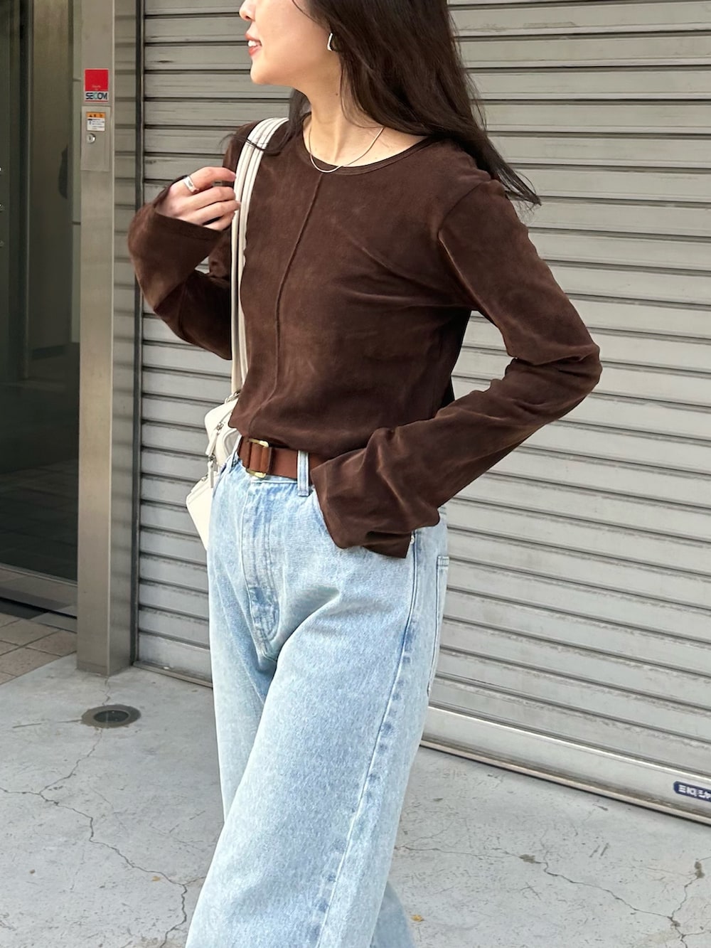ブラウン系のTシャツ/カットソー、ブルー系のデニムパンツ、ホワイト系のボストンバッグを着用したレディースの冬コーディネートの3枚目の写真