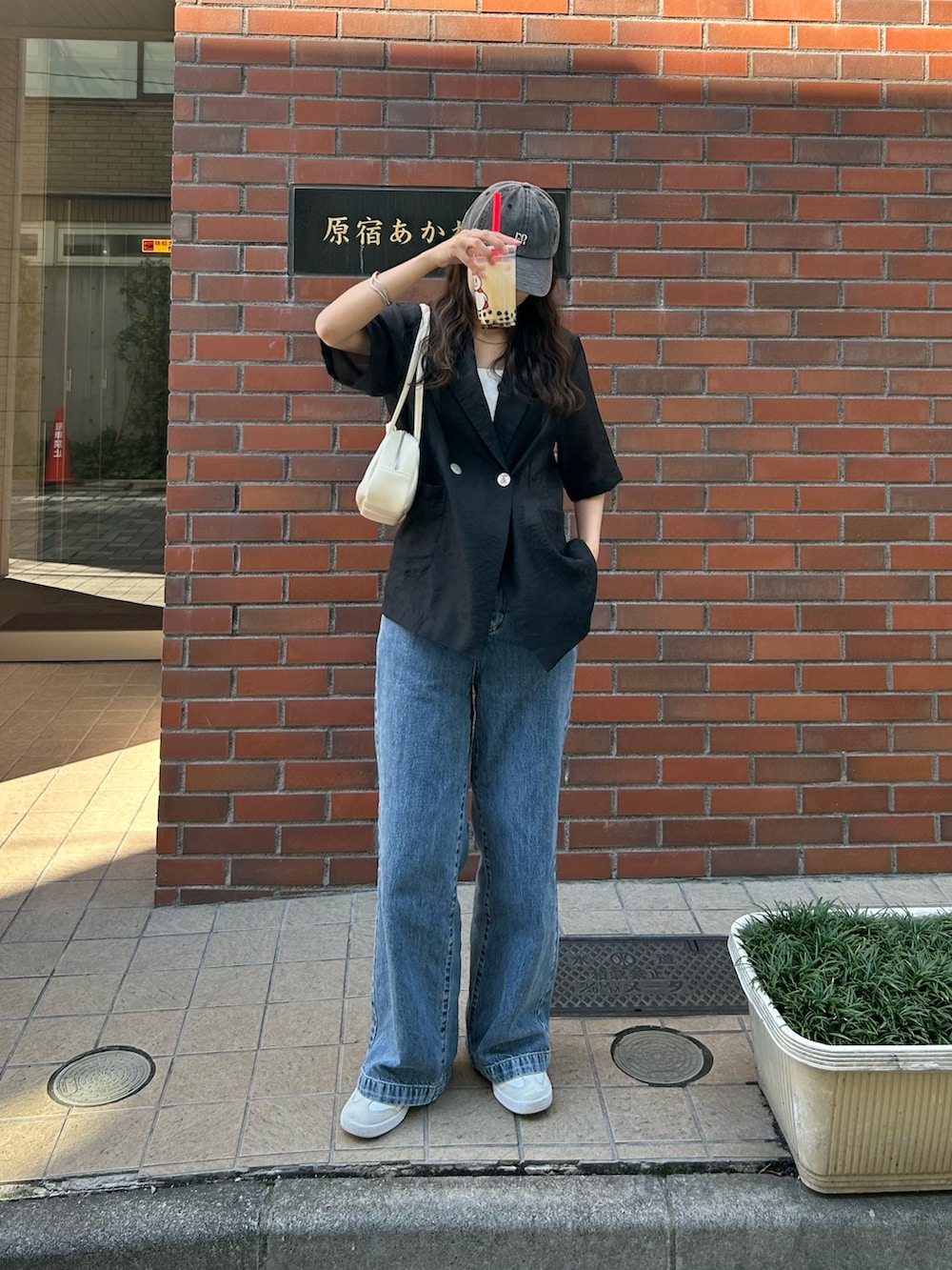 ブラック系のダウンジャケット/コート、ブルー系のデニムパンツ、ホワイト系のボストンバッグを着用したレディースの春コーディネートの2枚目の写真